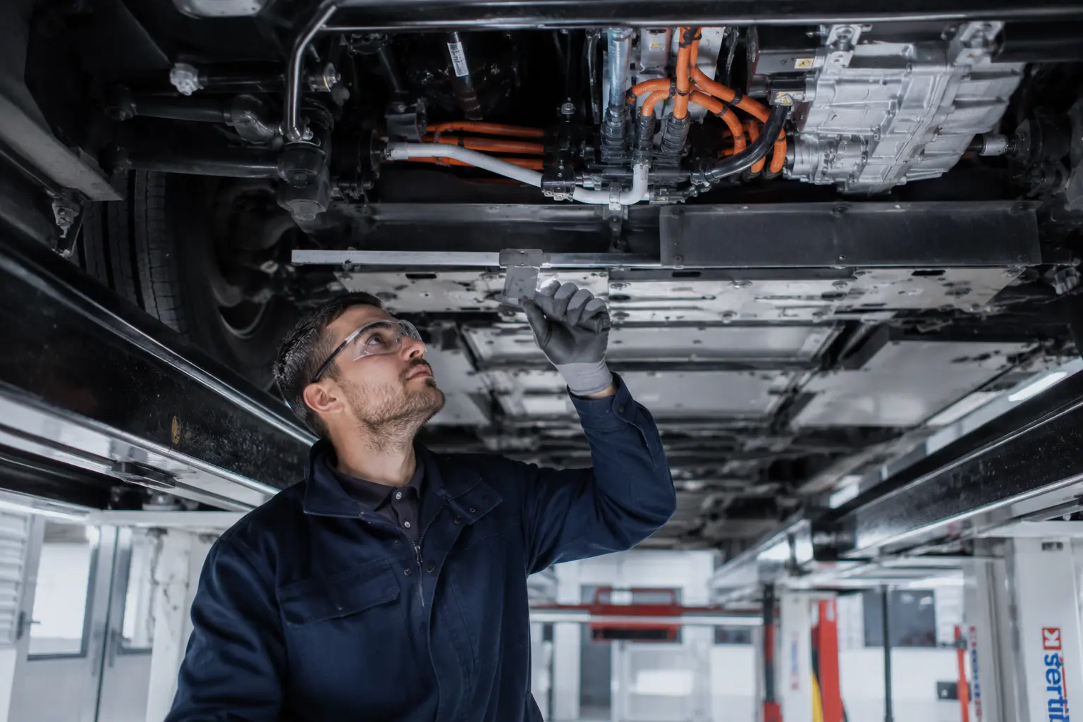 Technicien contrôlant la chaîne de traction haute tension d'un véhicule électrique